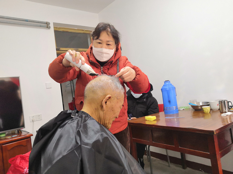 志愿者细心为吴老师理发.jpg